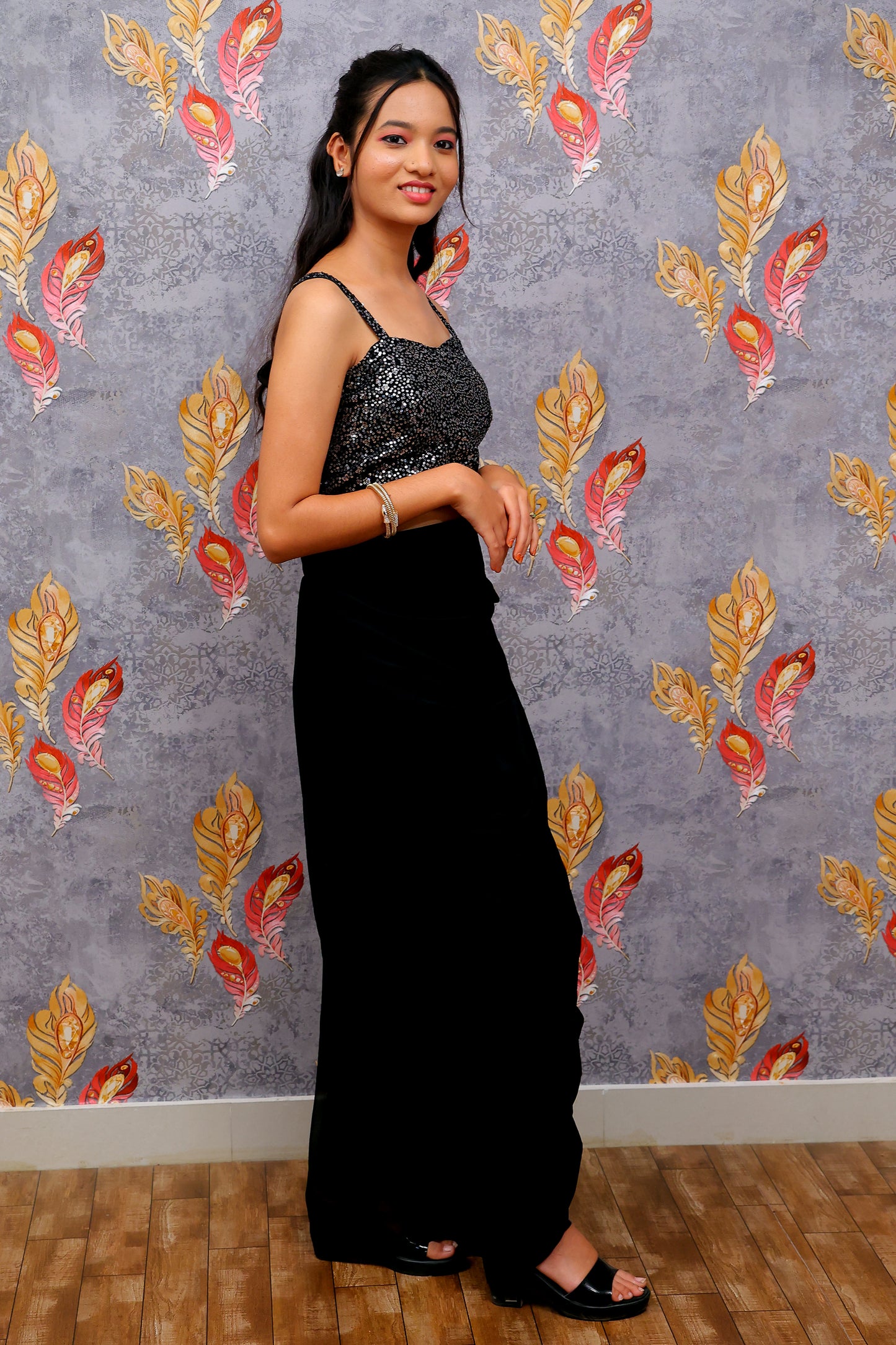 black draped skirt paired with a sequined, dark-colored crop top and a patterned shrug