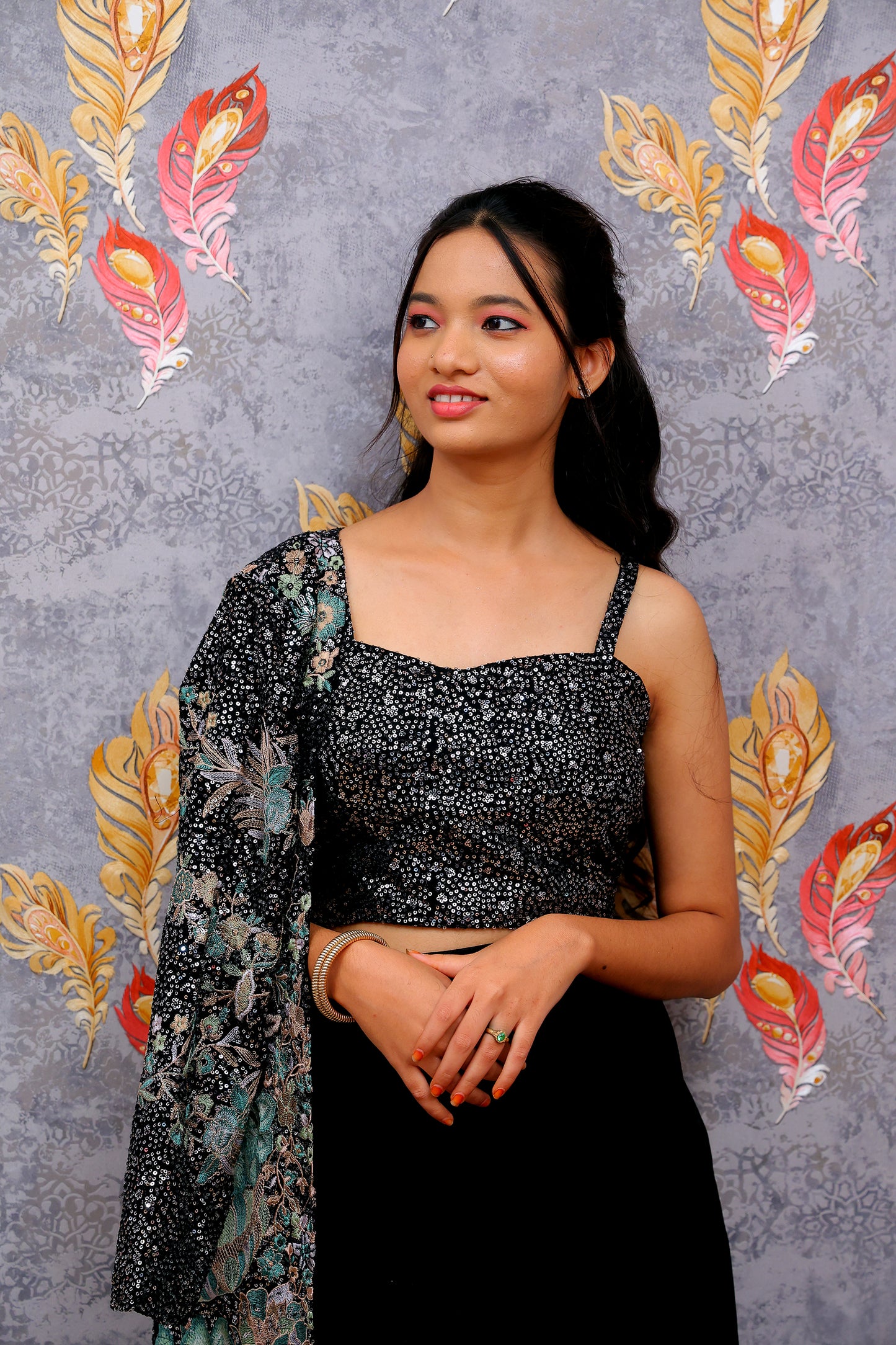 black draped skirt paired with a sequined, dark-colored crop top and a patterned shrug