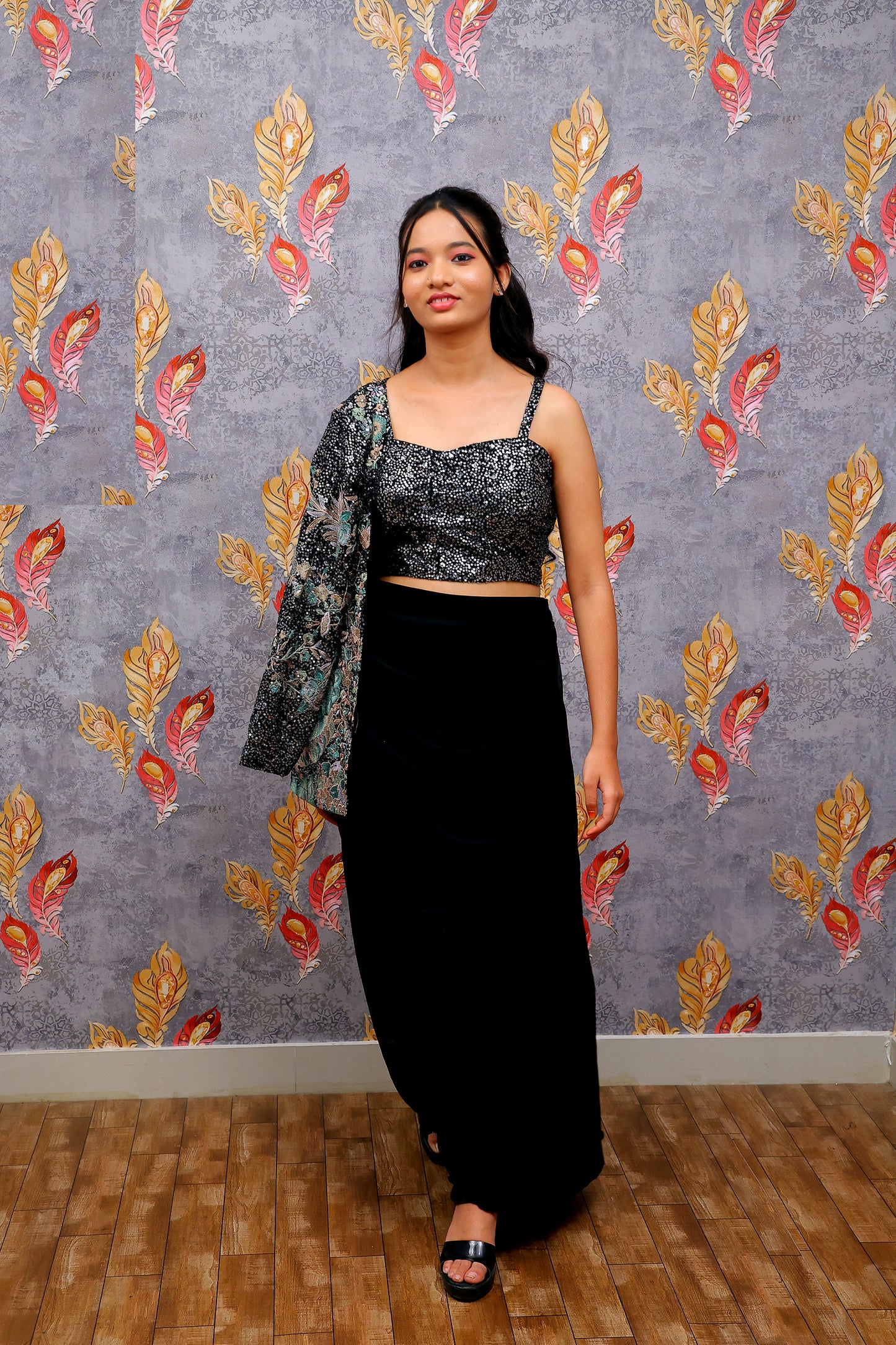 black draped skirt paired with a sequined, dark-colored crop top and a patterned shrug