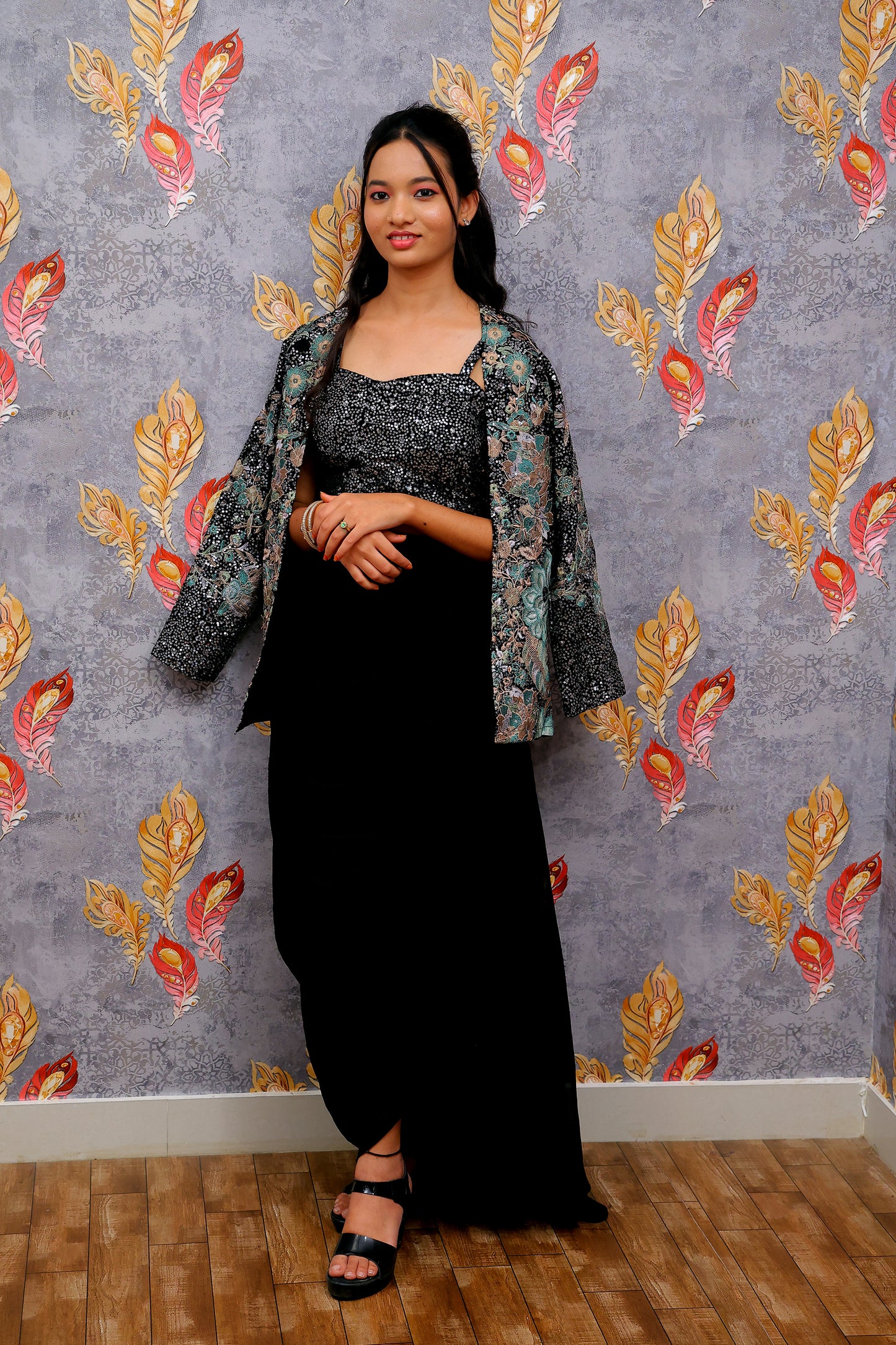 black draped skirt paired with a sequined, dark-colored crop top and a patterned shrug